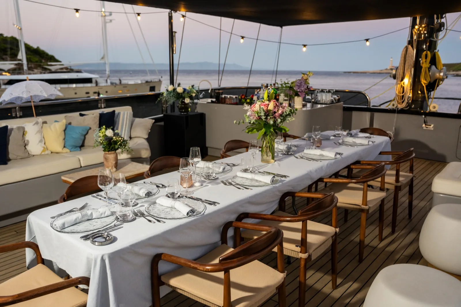 The sundeck dining table set for dinner with fresh flowers, the sea and an island behind