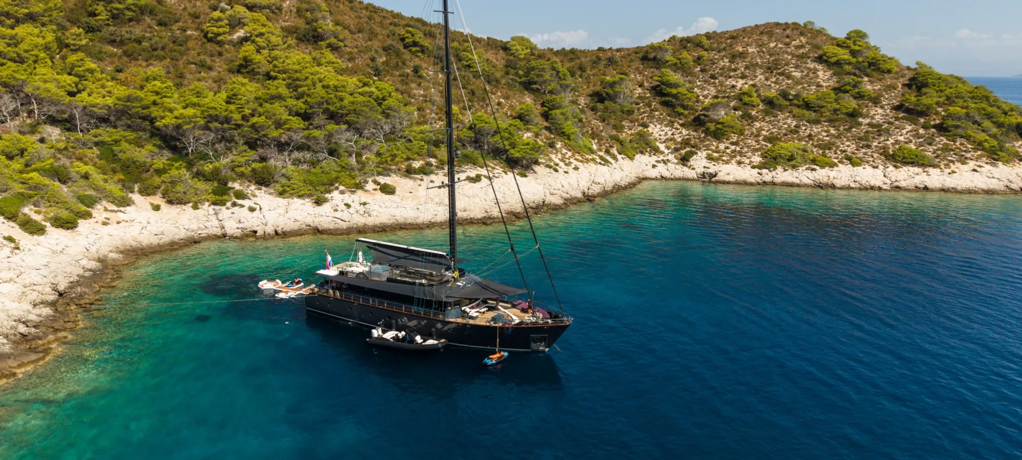 S/Y Rara Avis at anchor in a clear blue bay off a Croatian island, seen from above