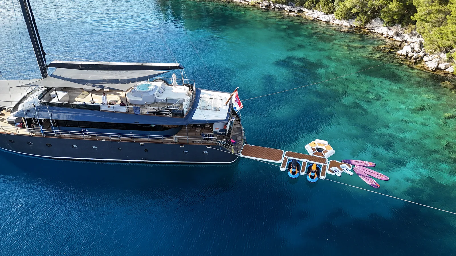 S/Y Rara Avis anchored in a turquoise bay with the swim platform and water toys out