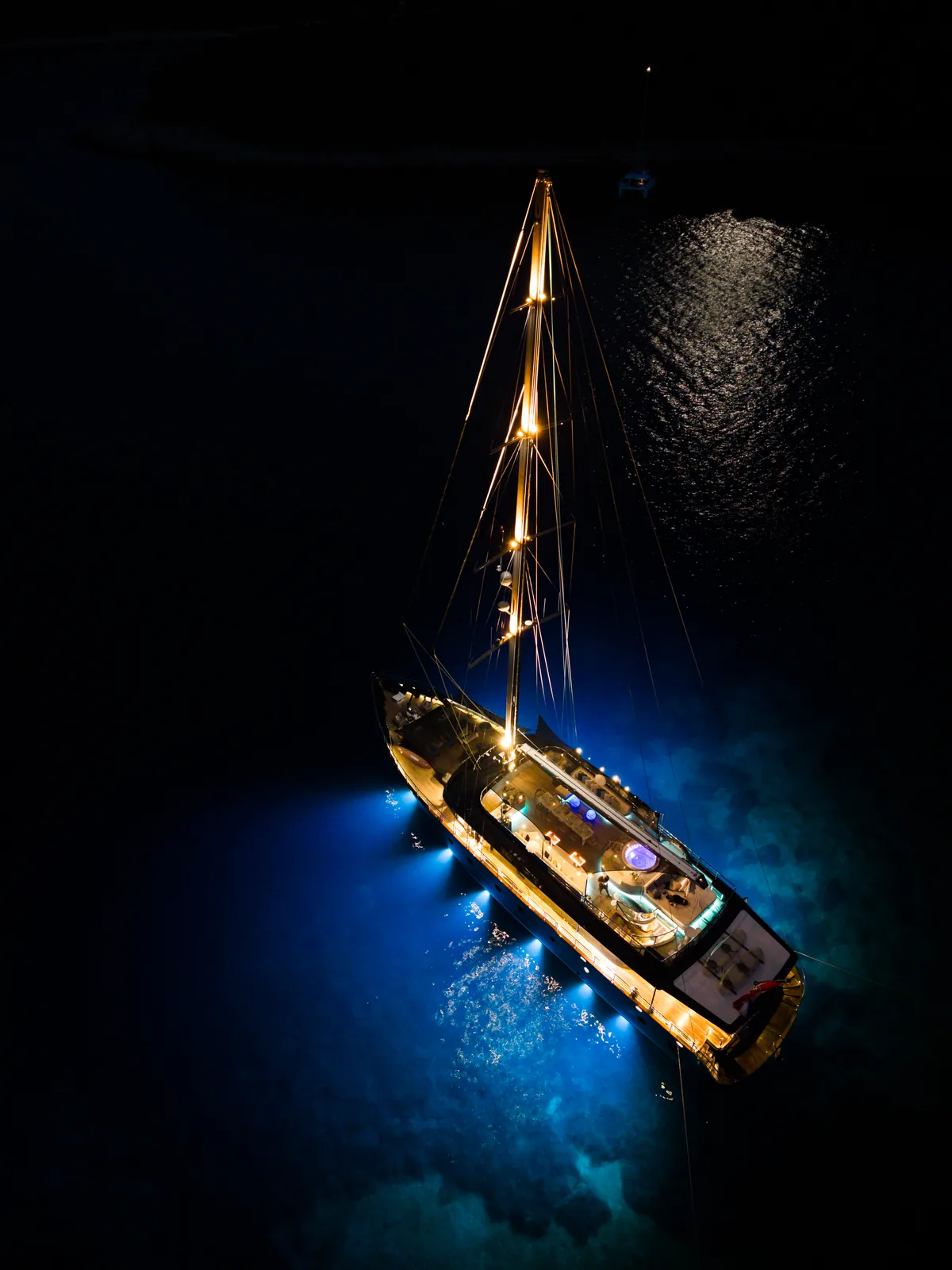 S/Y Rara Avis lit up at anchor at night, seen from above