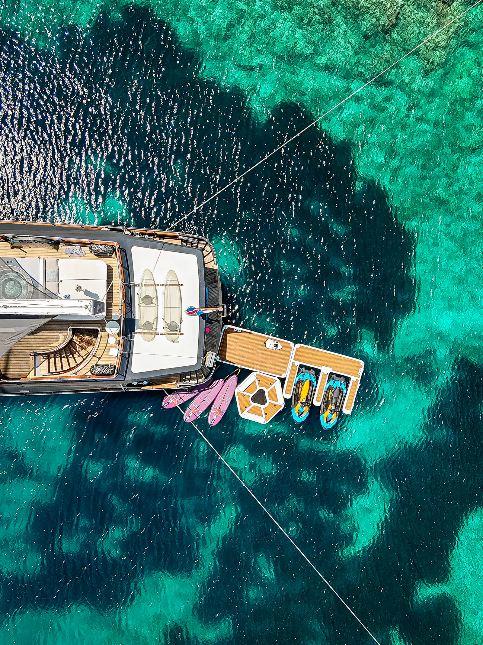 Swim platform of S/Y Rara Avis with jet skis, paddleboards and an inflatable trampoline