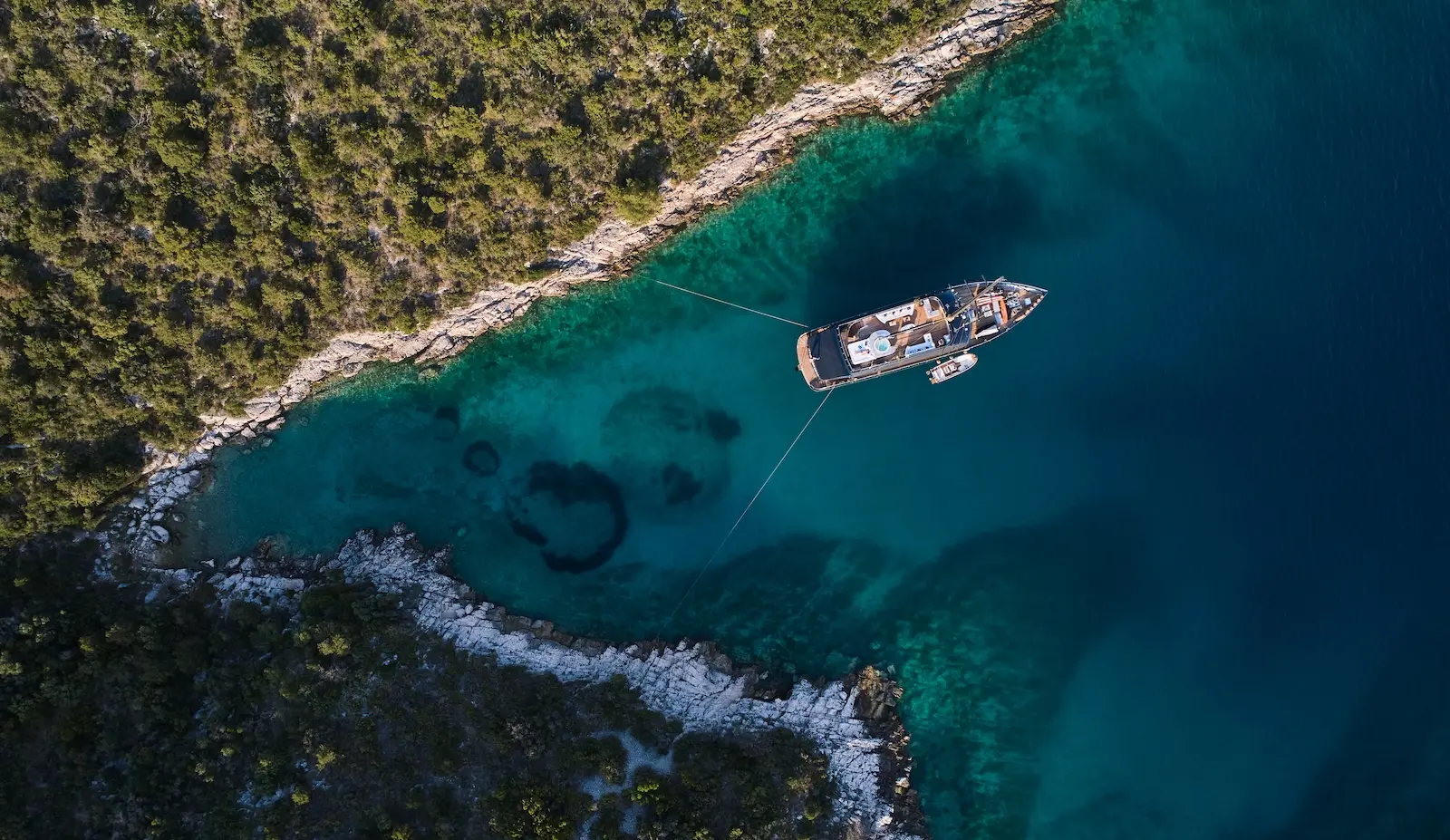 Aerial view of a luxury sailing yacht anchored alone in a turquoise Croatian bay